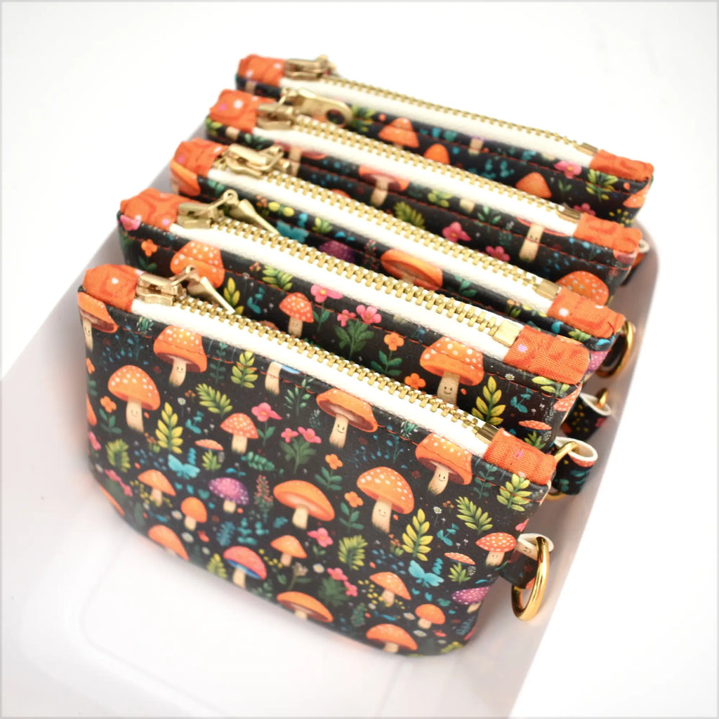 Set of four floral-patterned coin purses with zippers on a white background