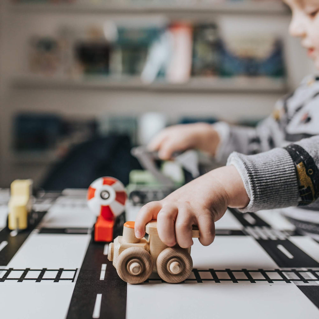 toddler playing with wooden train